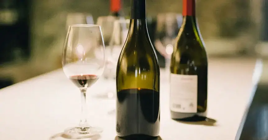 Rotweinflaschen auf einem Tisch mit Weingläser stehend